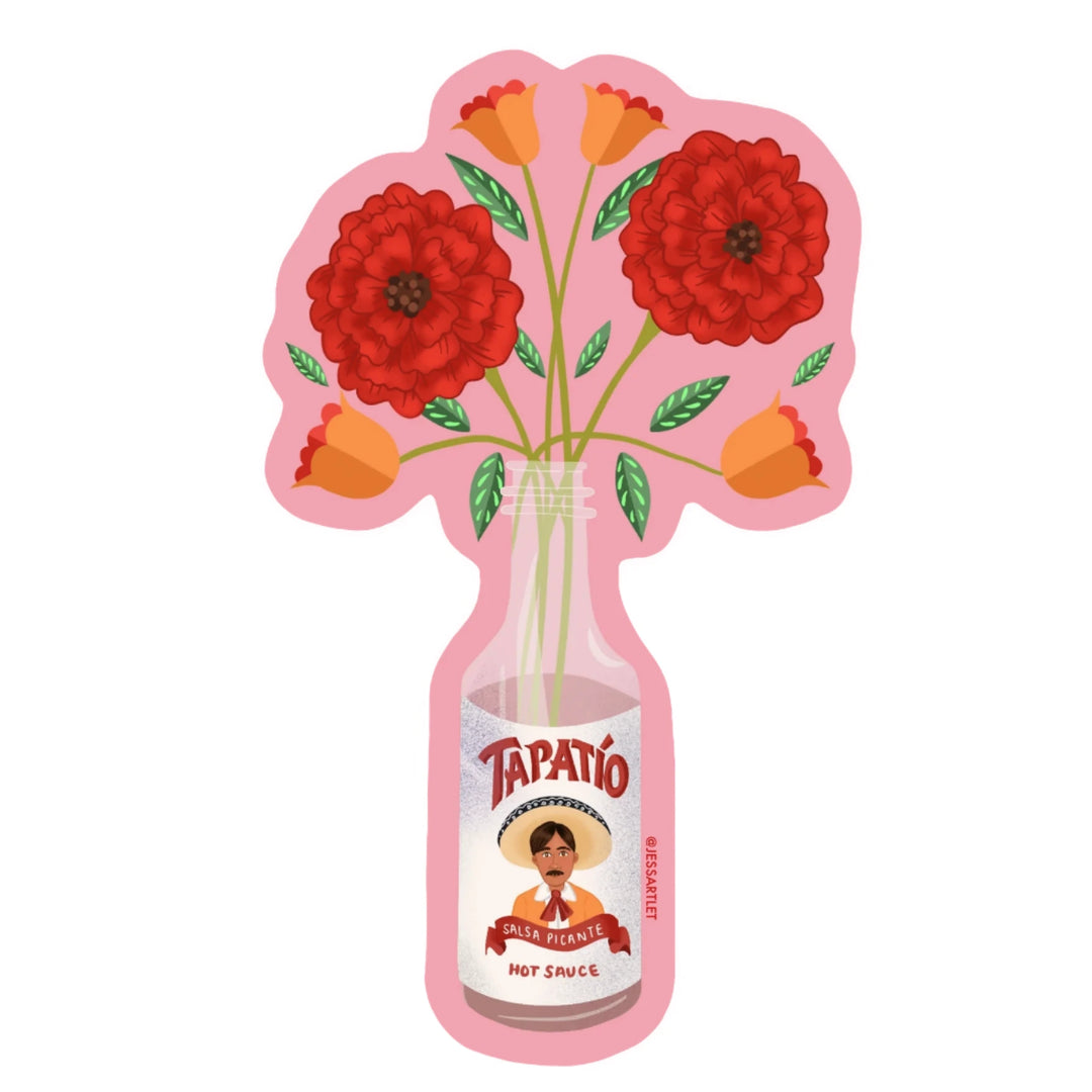 Sticker of a Tapatío hot sauce bottle used as a vase, holding bright red and orange flowers on a pink background.