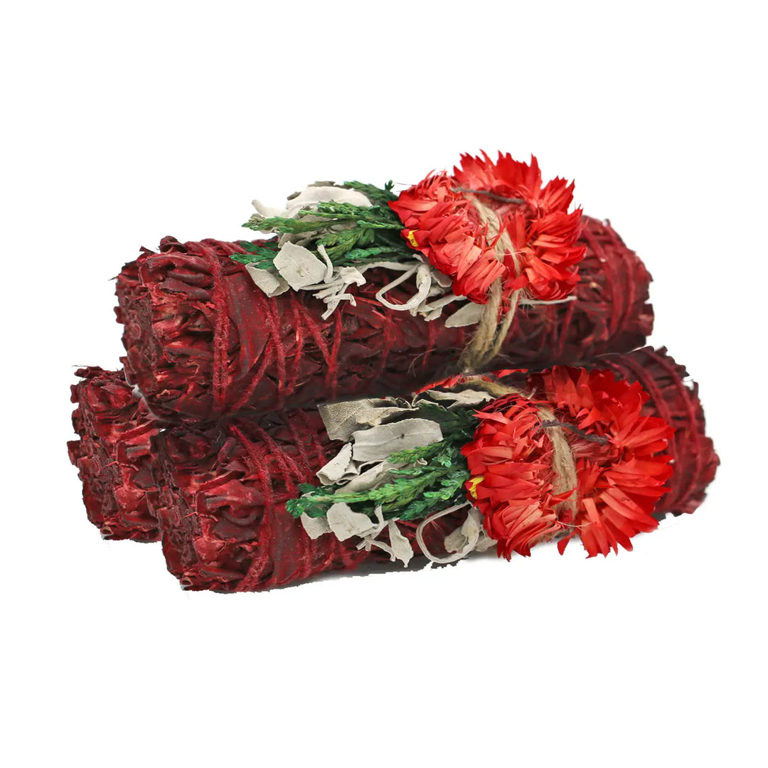 Three red dragon’s blood sage smudge sticks stacked together, each wrapped with botanicals and a bright red dried flower.