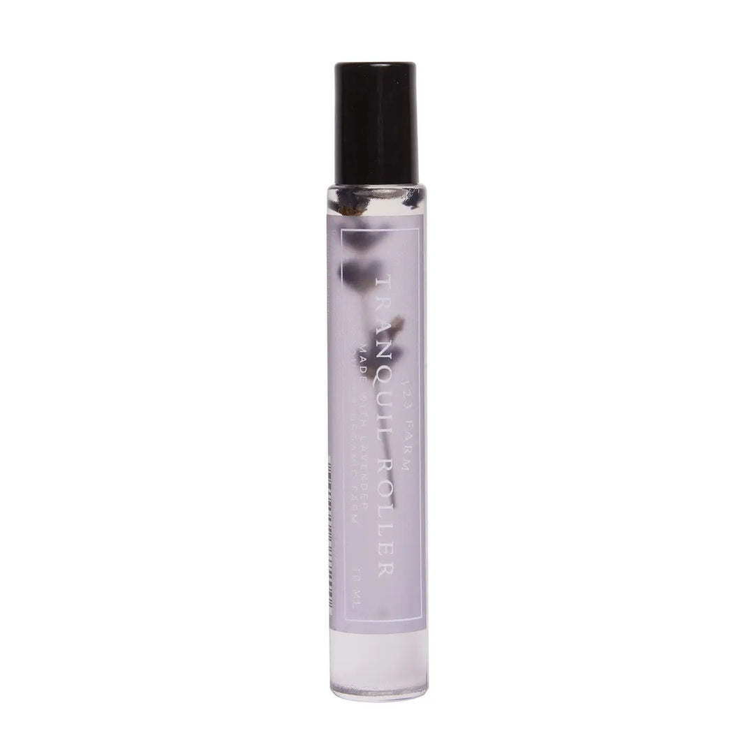 A sleek glass roller bottle labeled "Lavender Tranquil Roller," containing an organic essential oil blend with visible botanical elements inside, capped with a black lid.