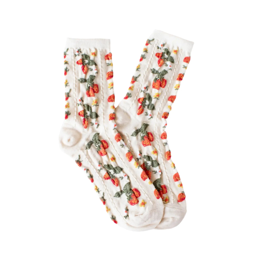 A pair of cream-colored socks featuring an all-over embroidered pattern of red strawberries, green leaves, and tiny white blossoms