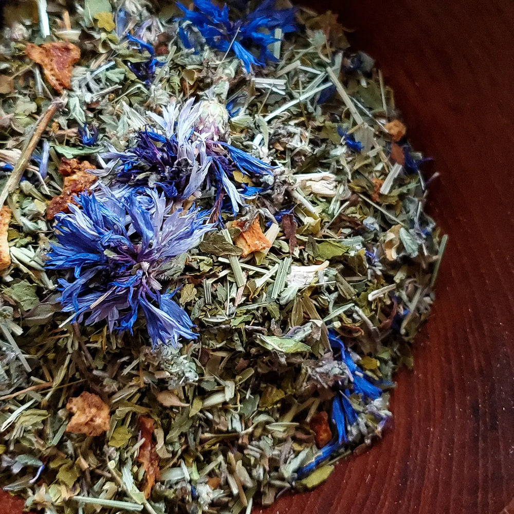 close up view of dried purple flower and loose leaf tea in a wooden bowl.