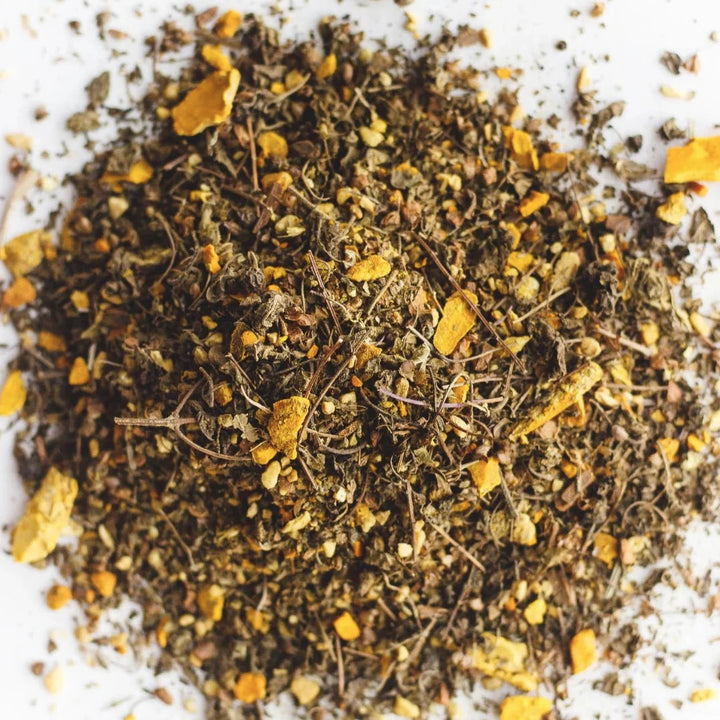 Loose herbal tea blend with visible turmeric pieces and dried botanicals.