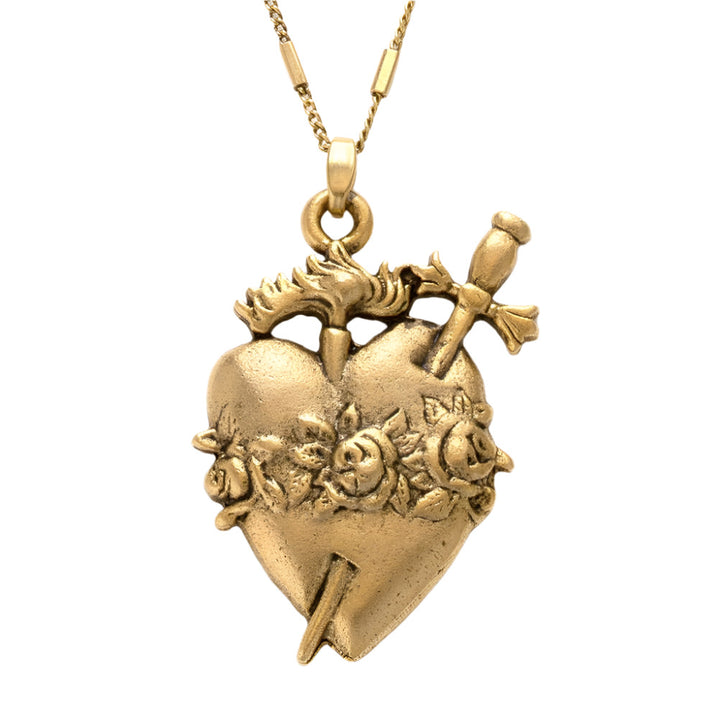 close up view of a gold-tone Immaculate Heart Necklace featuring an ornate sacred heart pendant with detailed roses, a flame, and a piercing dagger. The pendant hangs from a delicate gold chain against a white background.