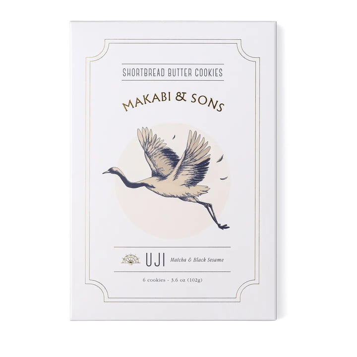 A box of Makabi & Sons Uji Shortbread Butter Cookies, featuring a minimalist illustration of a crane in flight. The packaging highlights the matcha and black sesame flavor of the cookies.