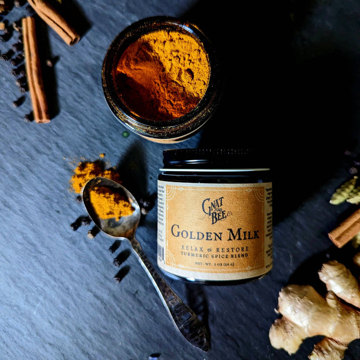 jar of the golden milk along side a spoon with the powder and an open jar of golden milk