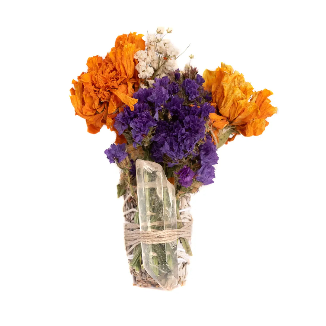 A vibrant smudge bundle featuring dried orange, purple, and white flowers tied together with twine, accompanied by a clear quartz crystal