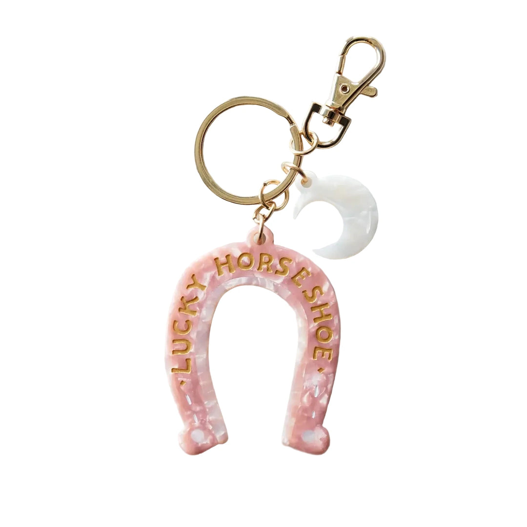 Pink marbled horseshoe bag charm with gold “Lucky Horseshoe” lettering, a white crescent moon charm, and gold key ring and clasp.