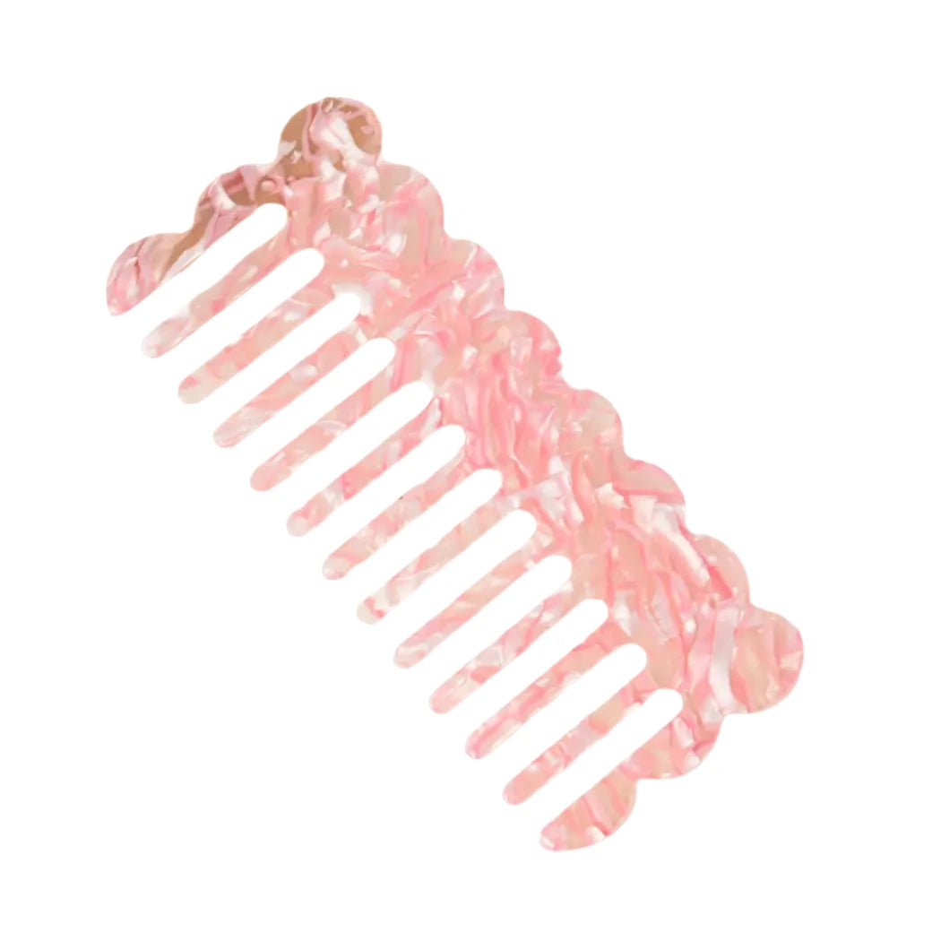 A pink marbled comb with a wavy, decorative edge and wide teeth, set against a white background