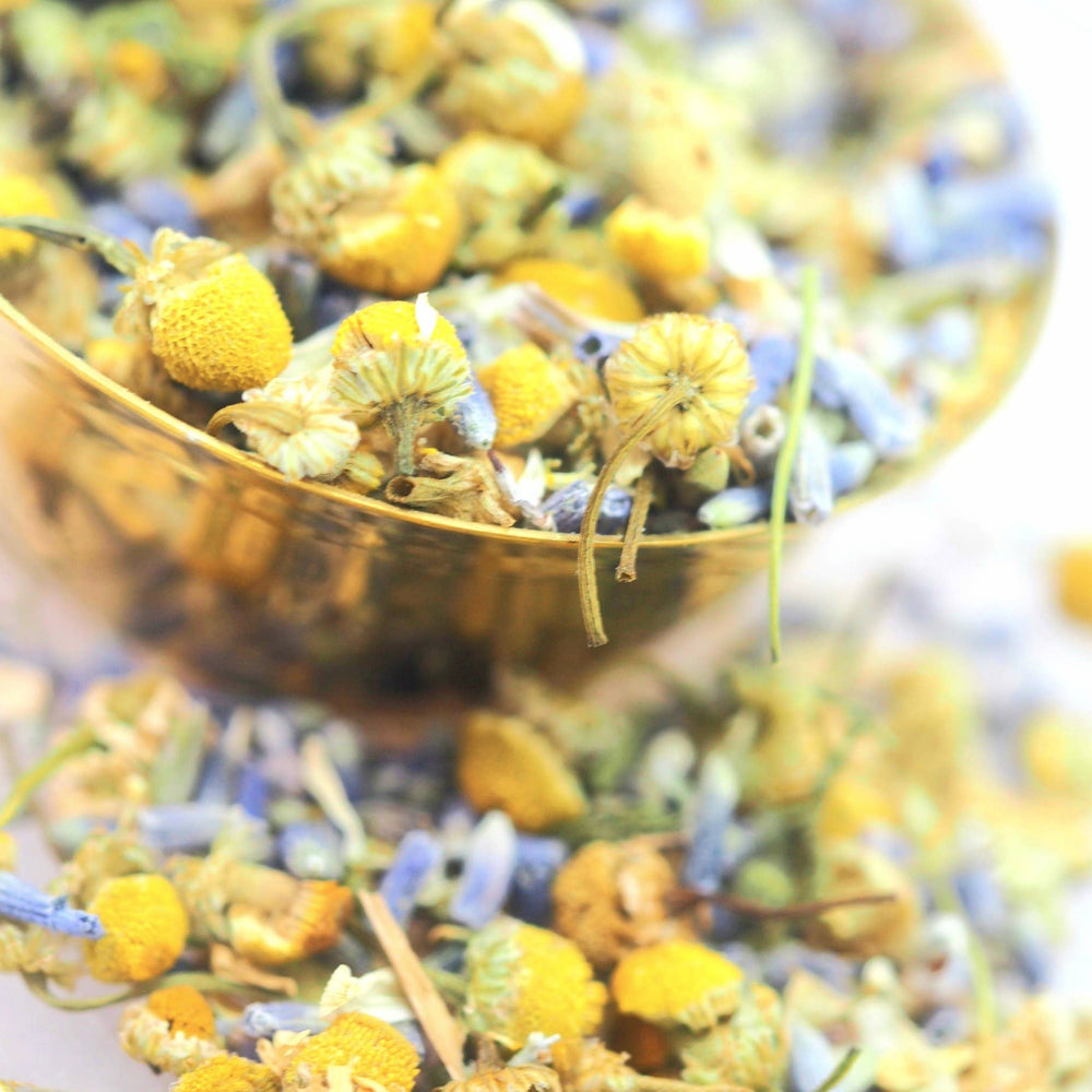 close up view of dried chamomile and lavender in a bowl and on a table. Brand: Loveyenergy & Blessings