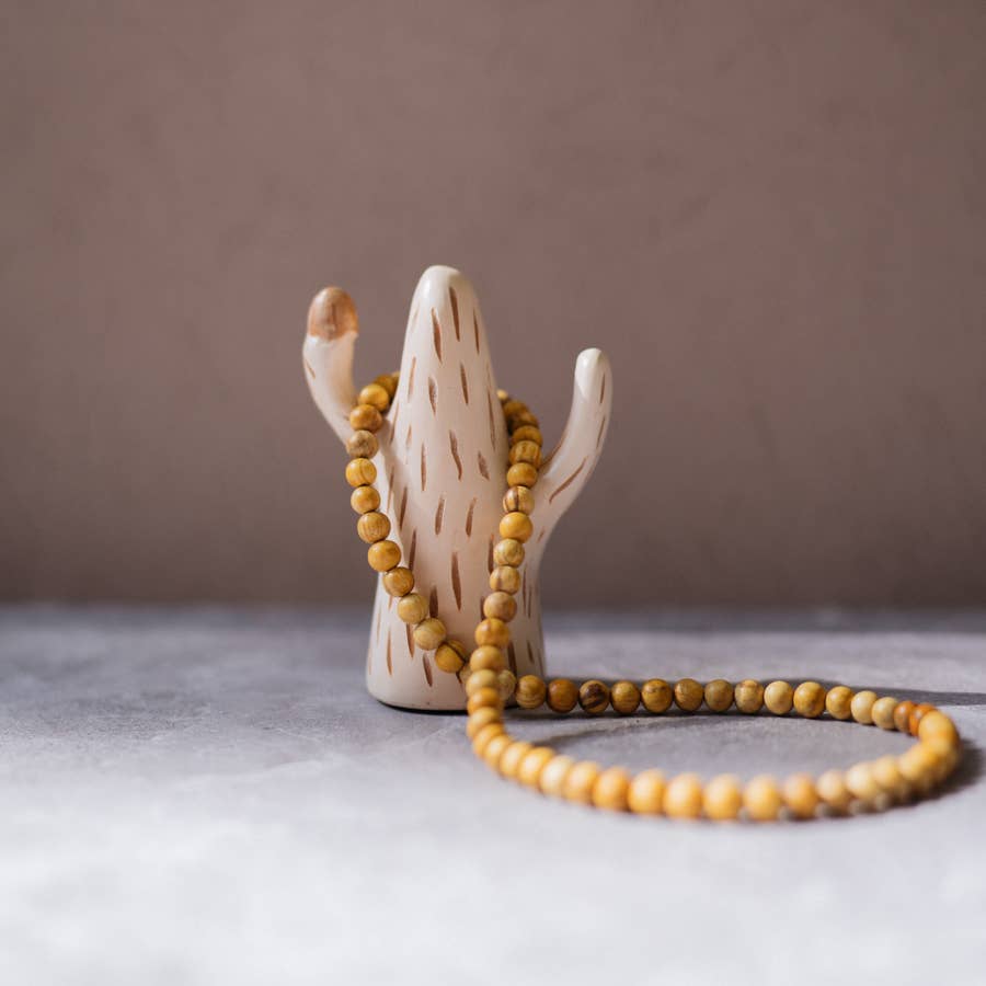 palo santo bead necklace laying over a sagauro shaped figure. Brand: Luna Sundara