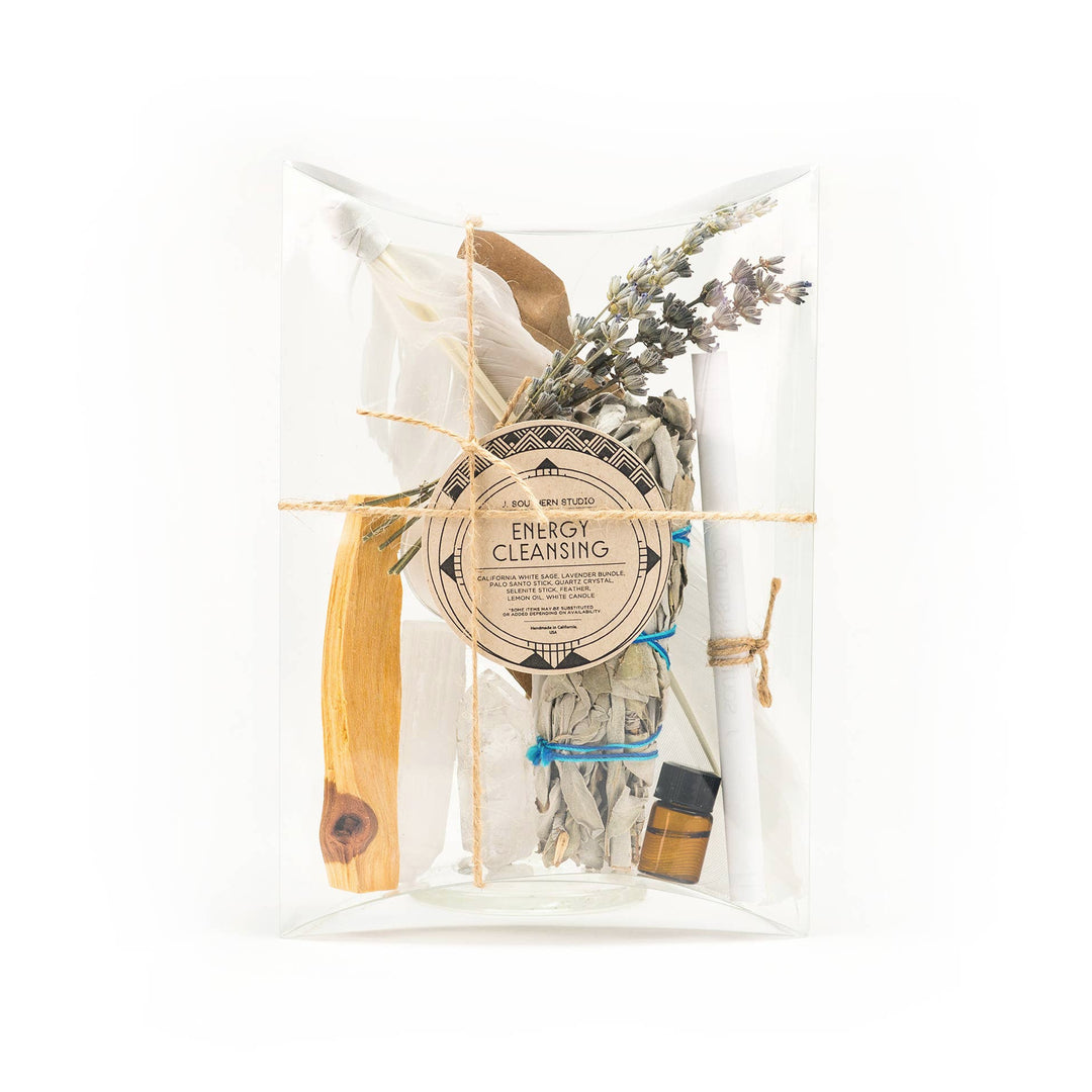 clear box with branded circle brown label and contains dried herbs and flowers, palo santo, lemon oil, candle and turkey feather.