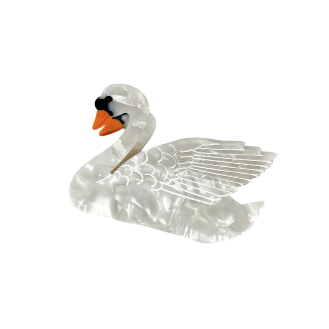 A swan-shaped hair clip with a pearlescent white finish, detailed wings, and an orange beak, set against a white background.