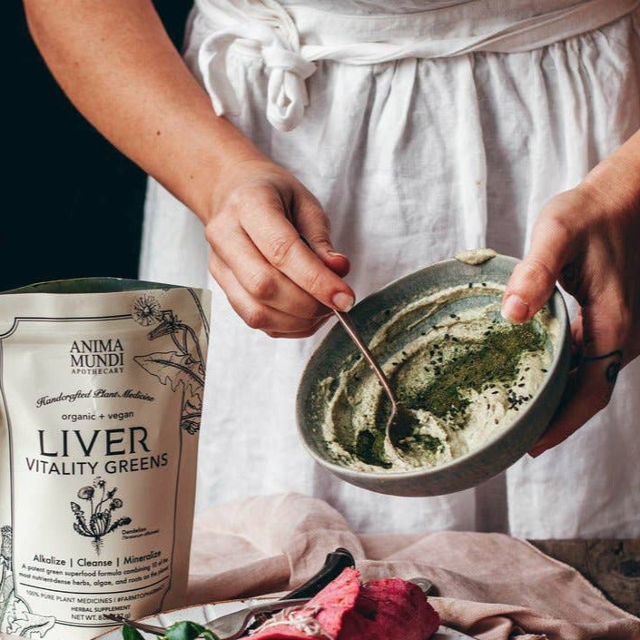 a woman mixing the liver vitality greens into a sauce with a pouch of it on the side. Brand: Anima Mundi Apothecary