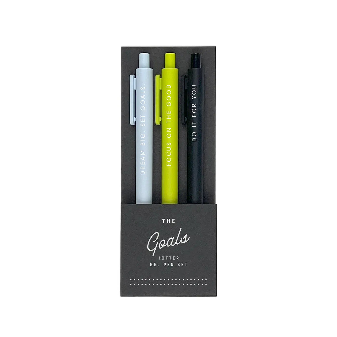 A set of three gel pens in a black packaging labeled "The Goals Jotter Gel Pen Set." The pens come in gray, lime green, and black, each featuring an empowering phrase in white lettering: "Dream Big. Set Goals," "Focus on the Good," and "Do It for You."