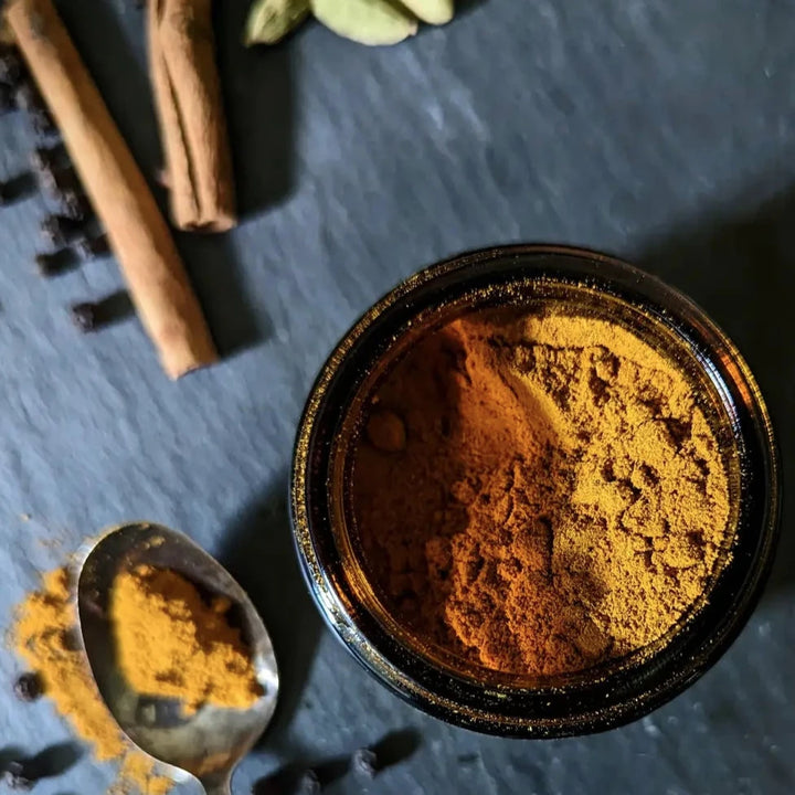 close up view of a jar of Golden Milk with a spoon alongside with Golden milk in it.