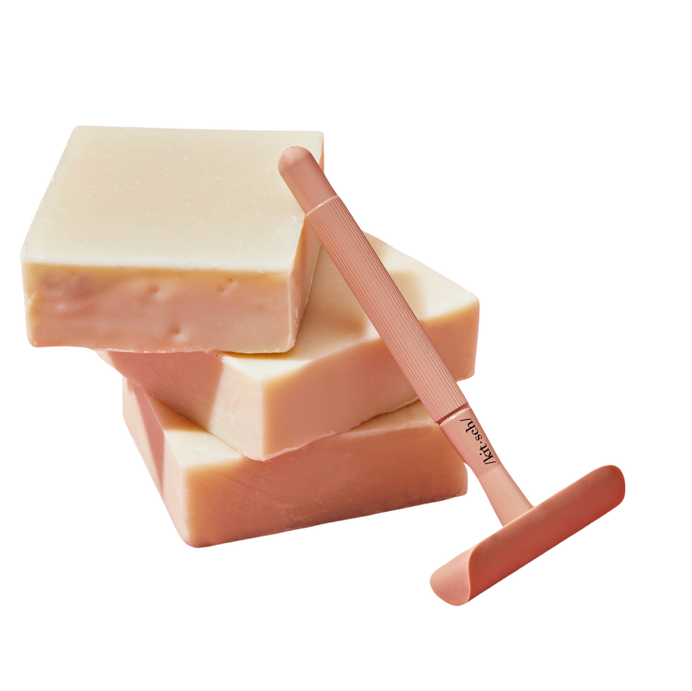 3 stacked bars of shave butter bar and a light pink shaver leaning on the bars. Brand: Kitsch