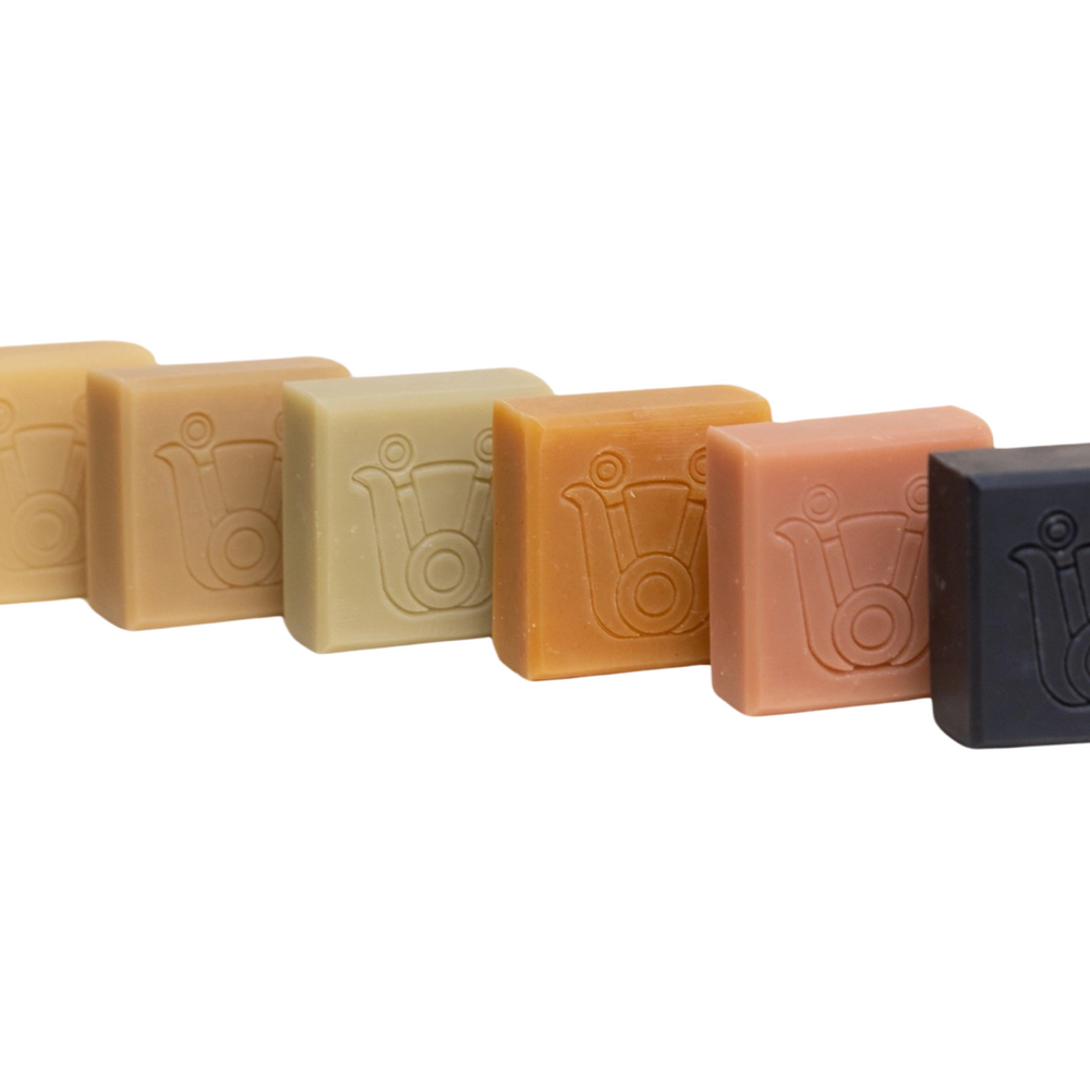 6 bars of soap of various color lined up one after another. Brand: Paca Botánica