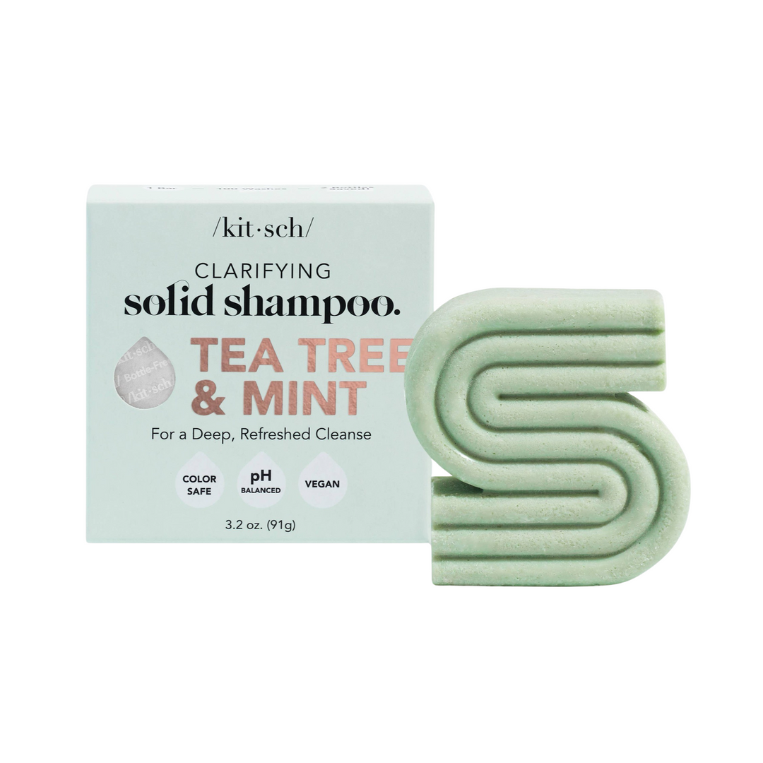 Sage colored branded box of shampoo bar and at its side a sage colored bar of shampoo in the shape of the letter "S.". Brand: Kitsch