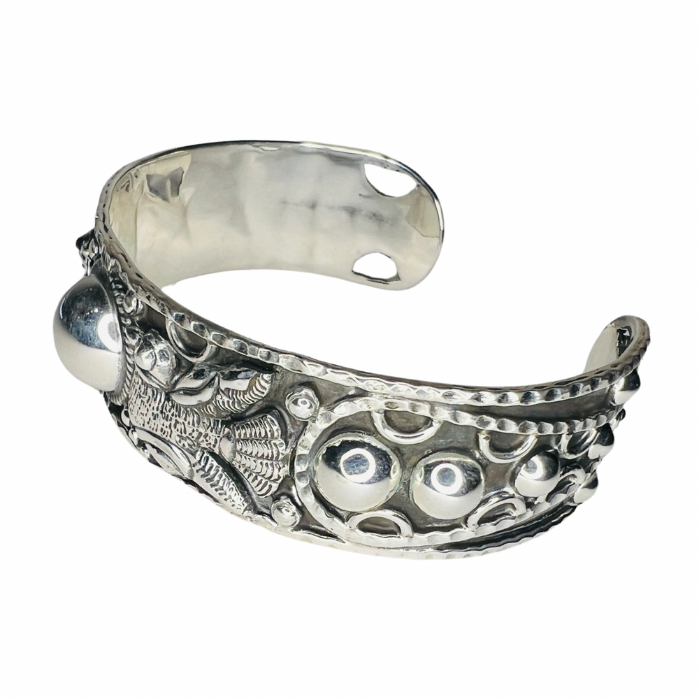 side view of a silver cuff bracelet that features a dove and circle designs