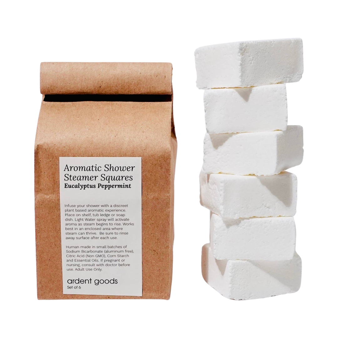 kraft bag with a white branded label and a stack of white steamer squares. Brand: Ardent Goods