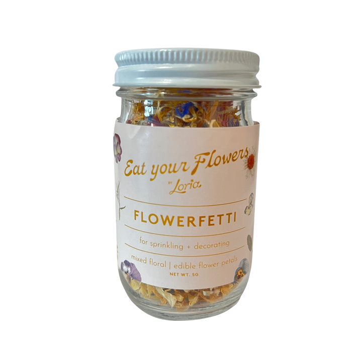 Clear 4 oz jar with dried flowers and herbs with a brand label and the name Flowerfetti in gold lettering.