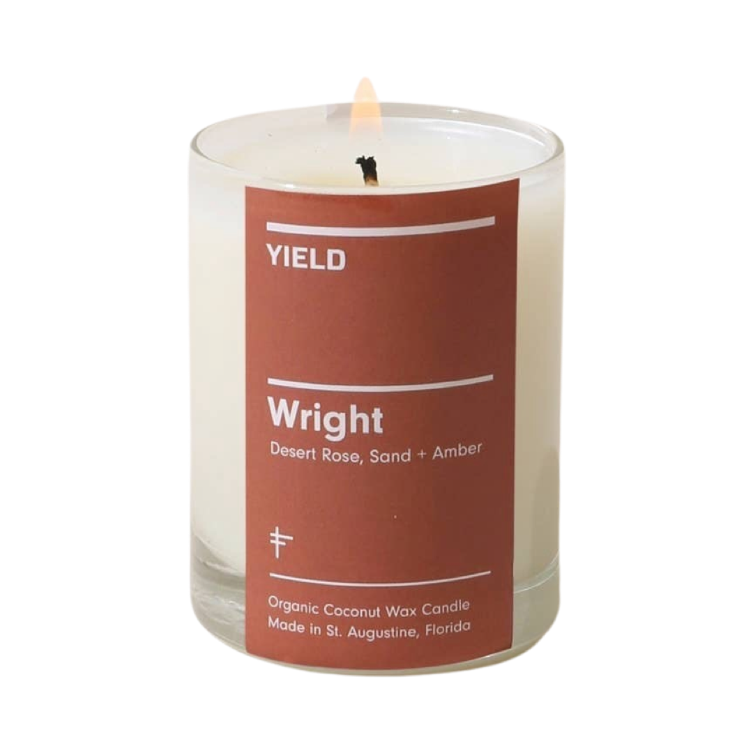 candle in a clear glass vessel with a brick red branded label