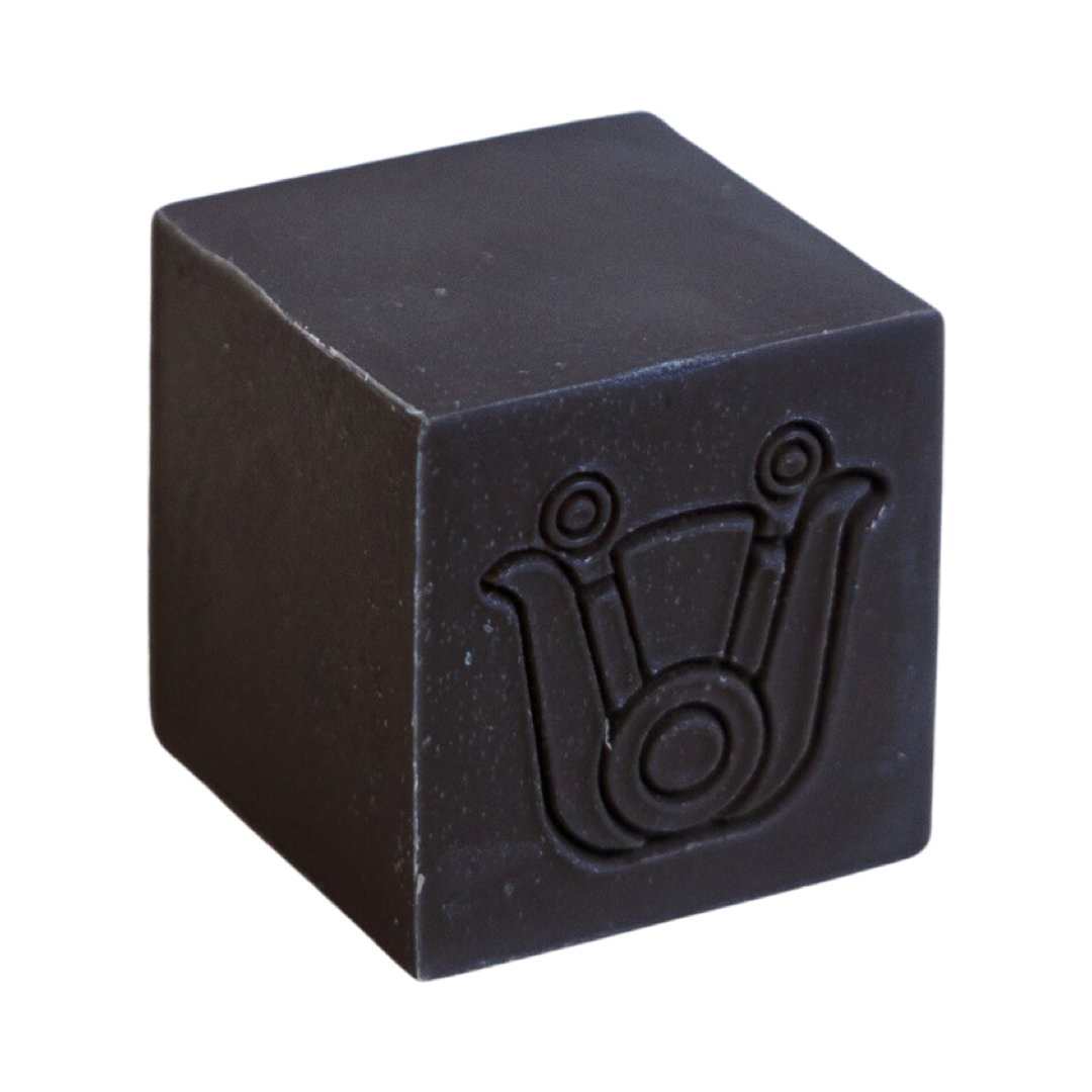 black colored cube shaped soap with an icon design. Brand: Paca Botánica