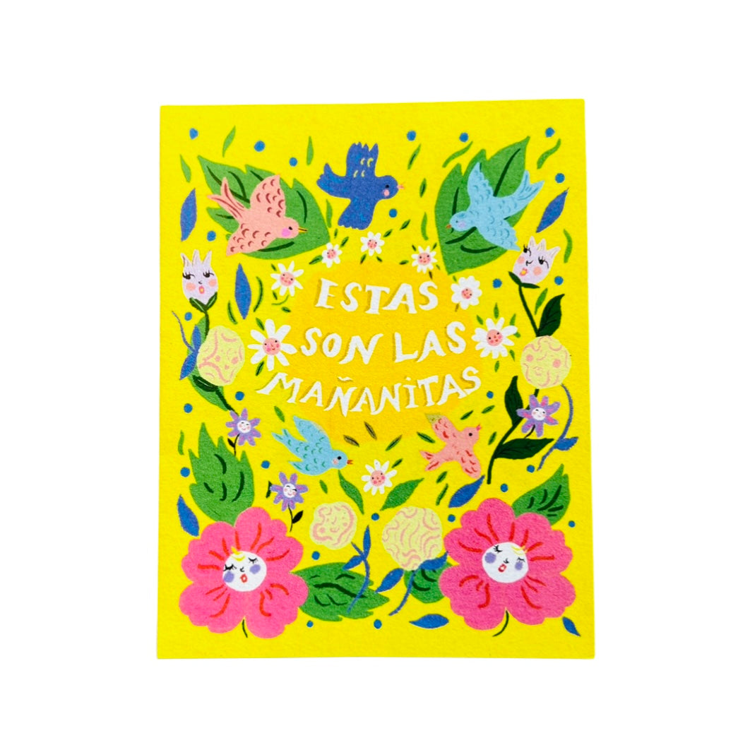 yellow card with a floral design with birds featuring thephrase Estas Son Las Mananitas in white lettering