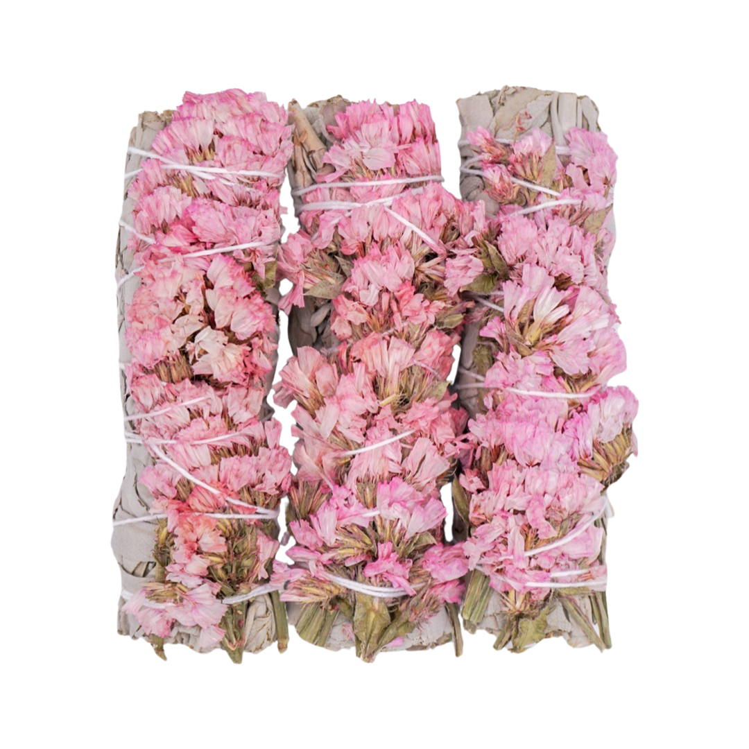 three sage bundles with pink sinuata flowers tied with white twine