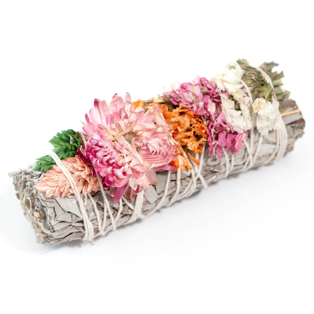 sage bundle with dried pink, peach and white flowers wrapped in white twine.
