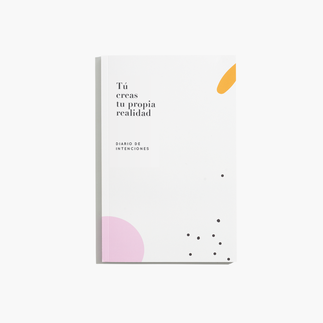 white journal with black dots and a half pink circle and orange oval with the title  Tu Creas tu Propia Realidad in black lettering