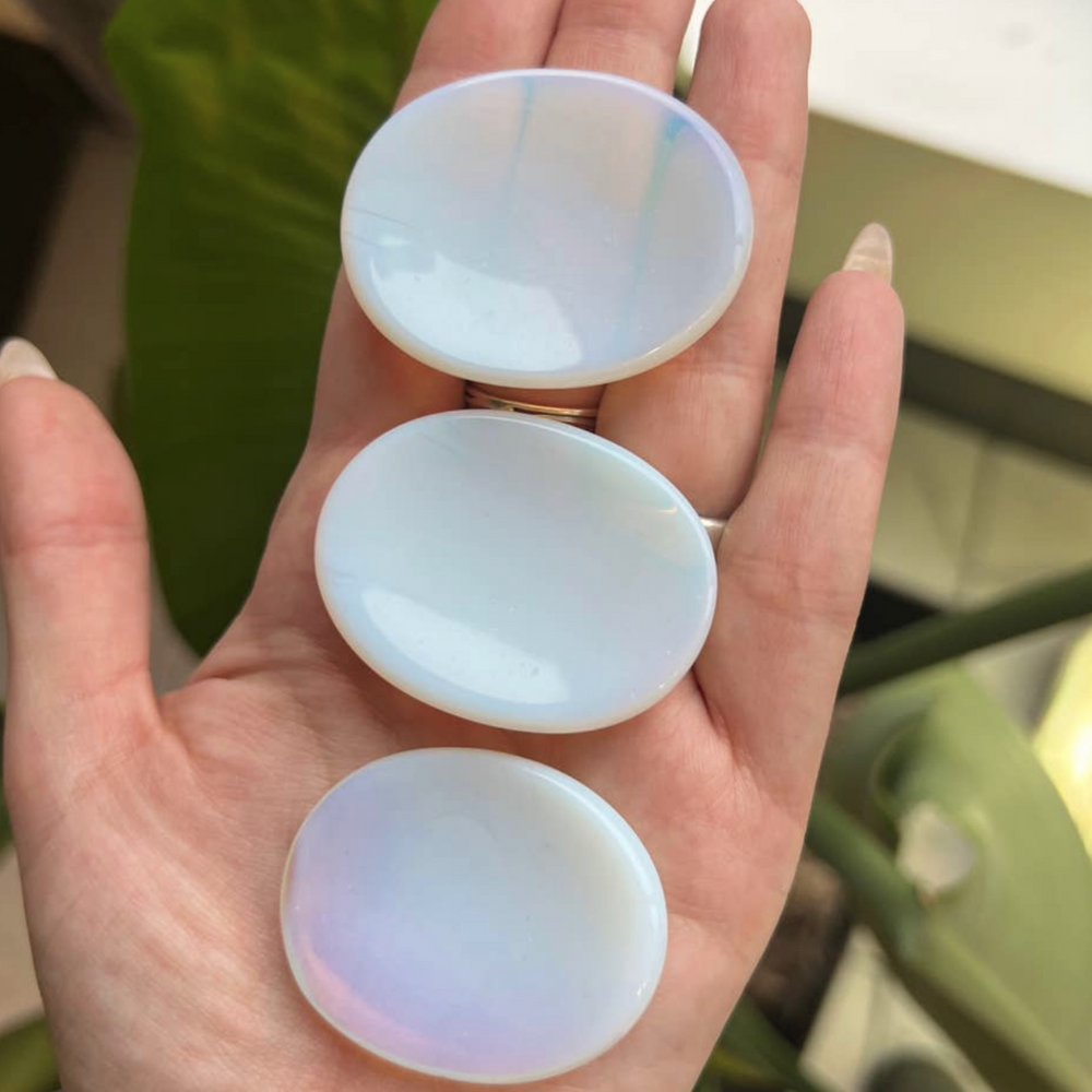 a hand holding 3 opalite crystal stones