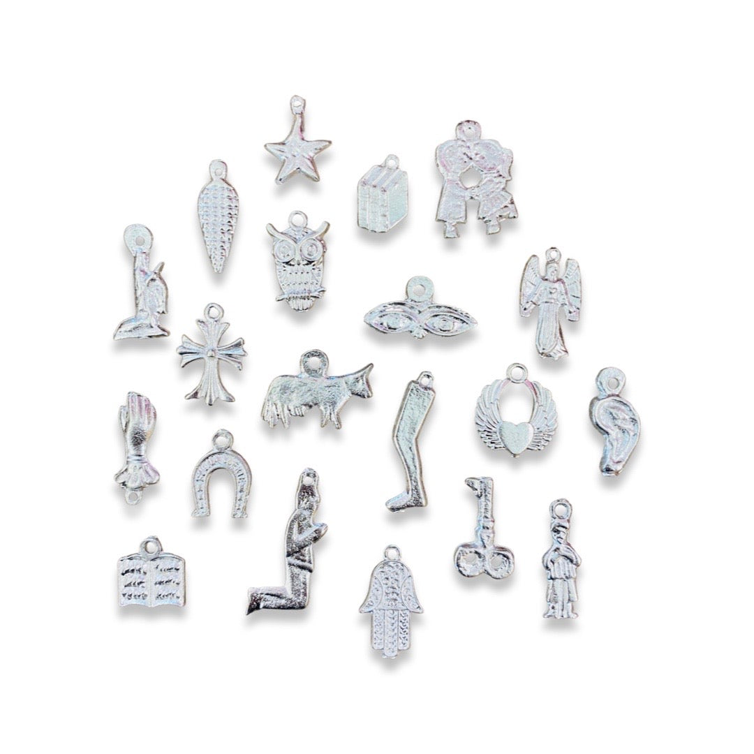 Top view of 20 silver milagro charms in various shapes including an owl, leg, angel and cross.