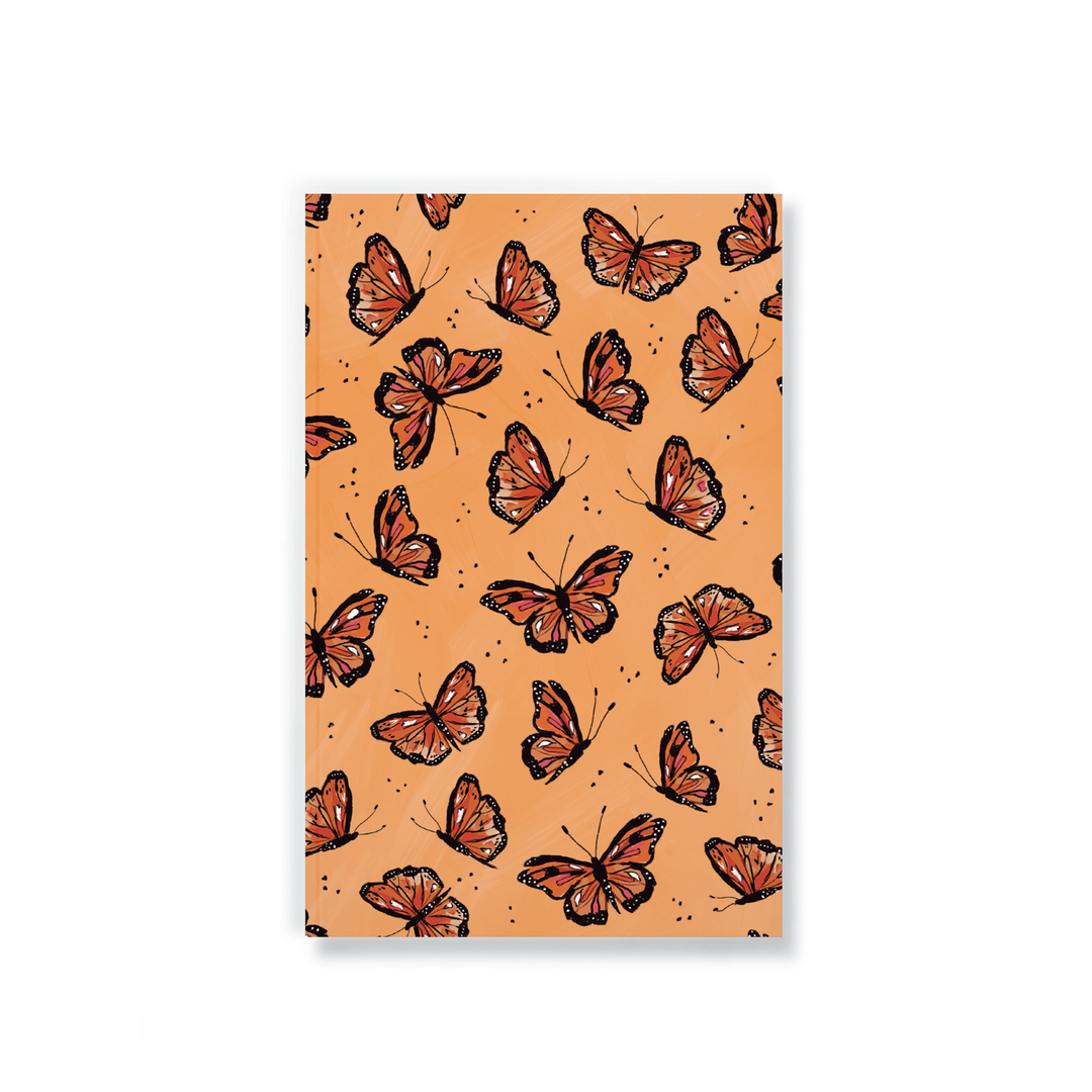 orange notebook with a monarch butterfly pattern design.