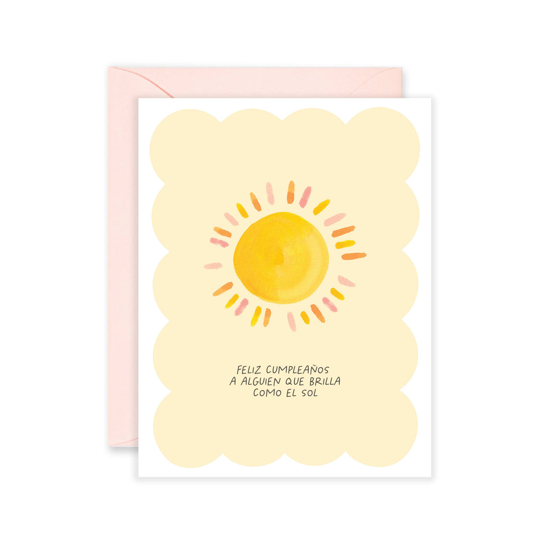 White and yellow card with the phrase Feliz Cumpleanos A Alguien Que Brilla Como El Sol that features a sun with multicolored rays.