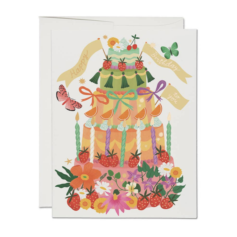 white card with an illustration of a colorful 3 tier cake and features fruits, candles, flowers and tassle decorating the cake along with 3 gold banngers that say happy birthday to you.